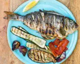 Gegrillte Dorade mit Zucchini, Aubergine, Paprika und Zwiebeln. Der frische Zitronenschnitz verspricht den vollen Dorade Geschmack.