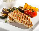Gebratener Seelachs mit gegrilltem Gemüse wie Zucchini, Aubergine und Tomaten, garniert mit Kräutern.