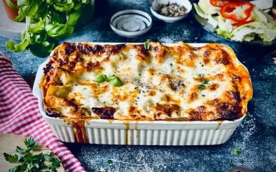 Herzhafte vegetarische Lasagne mit geschmolzenem Käse und frischem Basilikum, serviert in einer weißen Auflaufform.