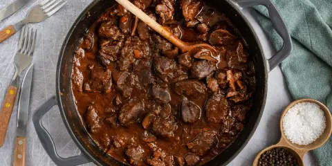 Herzhafter Rehgulasch in dunkler Sauce, bereit zum Schmoren. Die Frage "reh gulasch wie lange schmoren" wird hier visuell beantwortet: lange und langsam für zartes Fleisch.