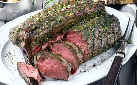 Saftige Hirschkeule, perfekt gebraten und mit Kräutern verfeinert, liegt auf einem Teller. Ein Festmahl für jeden Jäger.