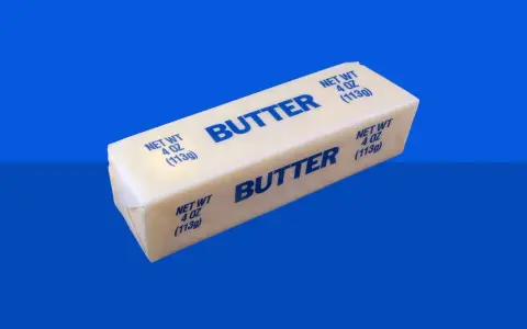 Ein Block Butter auf blauem Hintergrund. Bei Diabetes ist die Frage, wie viel Butter erlaubt ist.