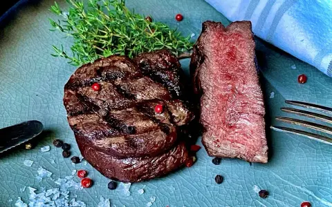 Perfekt gegrilltes Rinderfilet mit zarten rosa Kern, garniert mit Thymian, Pfeffer und grobem Salz. Ein Genuss für Fleischliebhaber!