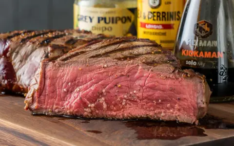 Saftiges, medium-gebratenes Steak auf einem Holzbrett, bereit zum Genuss. Perfekt zum Grillen einlegen mit den abgebildeten Saucen.