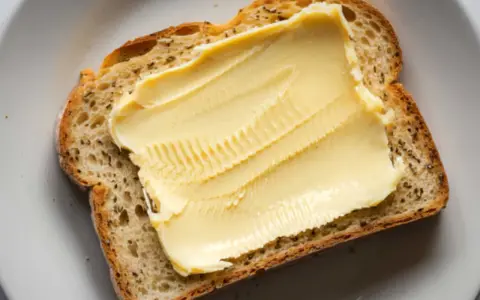 Eine Scheibe Brot mit einer dicken Schicht Butteralternative, die gut für die Cholesterinwerte ist.