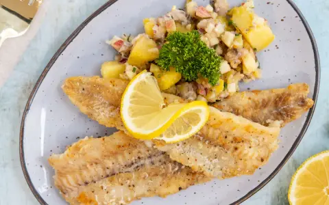 Gebratene Seelachsfilets mit Kartoffelsalat und Zitrone. Leckere Seelachsfilet Rezepte Pfanne für ein schnelles Abendessen.