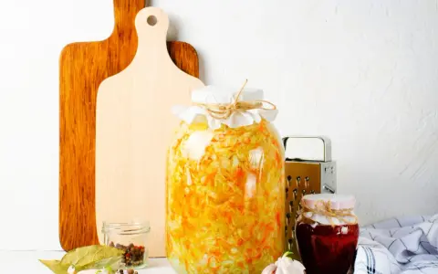 Großes Glas mit Sauerkraut, bereit zum **fermentieren im Schraubglas**. Daneben Gewürze, Knoblauch und ein kleines Glas Marmelade.