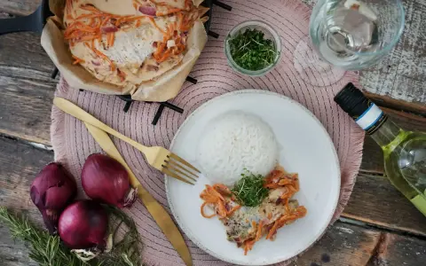 Ein Rotbarschfilet mit Senfsauce, serviert mit Reis und garniert mit Kresse. Dazu passen rote Zwiebeln und ein Glas Weißwein.