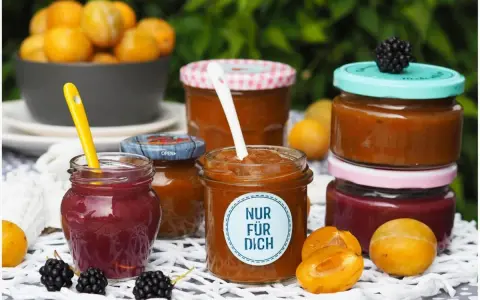 Marmelade ohne Gelierzucker haltbar machen: Mehrere Gläser mit selbstgemachter Marmelade, Früchten und Beeren.