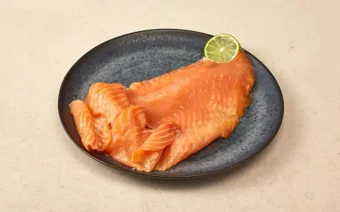 Räucherlachs auf dunkler Platte, garniert mit einer Limettenscheibe. Perfekt für einen Caipirinha-Lachs-Genuss.