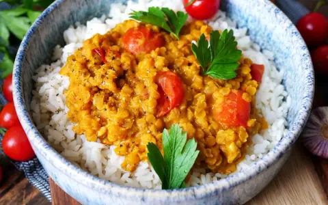 Herzhaftes rote Linsen Curry mit Reis, garniert mit frischer Petersilie und Kirschtomaten. Ein Genuss für die Sinne!