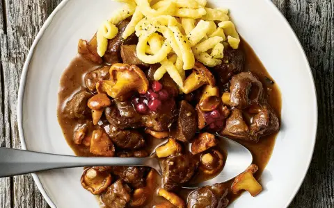 Herzhaftes Rehgulasch mit Rotwein, Pilzen und Preiselbeeren, serviert mit Spätzle. Ein köstliches Rehgulasch Rezept.