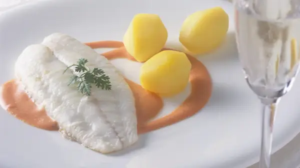 Ein zartes Steinbuttfilet mit Petersilie, serviert mit Salzkartoffeln und einer cremigen Sauce. Der feine Steinbutt Geschmack verspricht ein kulinarisches Erlebnis.