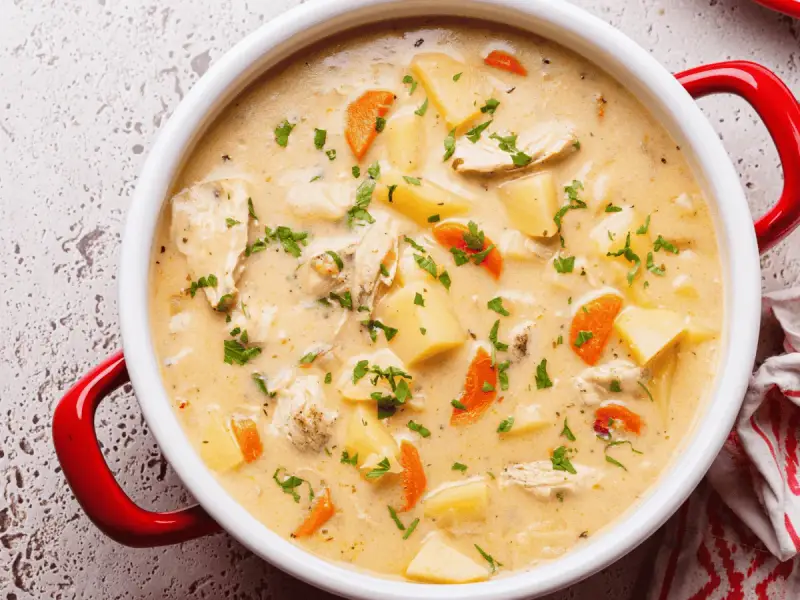 Cremige Hühnersuppe mit Kartoffeln und Karotten, ein Klassiker unter den Suppen Rezepten, garniert mit Petersilie.